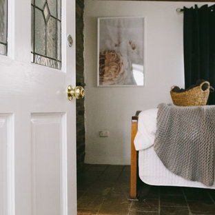 Foto de dormitorio campestre, pequeño, con paredes blancas, suelo de pizarra y estufa de leña