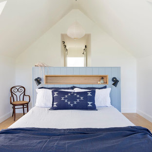 Photo of a small country guest bedroom in Wollongong with white walls, light hardwood floors and brown floor.