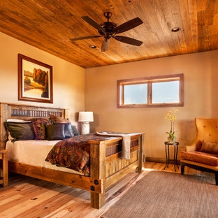Imagen de habitación de invitados rural, de tamaño medio, sin chimenea, con paredes beige, suelo de madera clara y suelo marrón