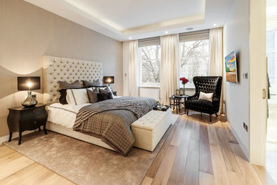This is an example of a large traditional bedroom in London with beige walls and medium hardwood flooring.