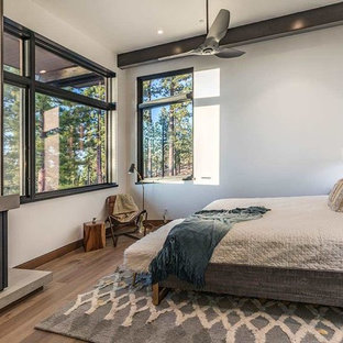 Diseño de habitación de invitados moderna, sin chimenea, con suelo de madera clara, marco de chimenea de hormigón y suelo marrón