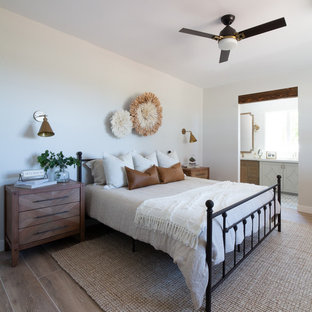 Mittelgroßes Landhausstil Hauptschlafzimmer mit weißer Wandfarbe, Porzellan-Bodenfliesen, Eckkamin, Kaminumrandung aus Backstein und beigem Boden in Phoenix