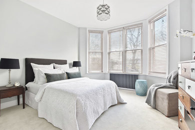 Photo of a bedroom in London with grey walls, carpet and beige floors.