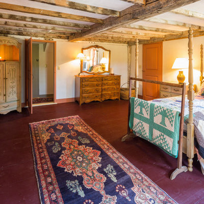 Example of a cottage master painted wood floor and red floor bedroom design in Boston with white walls, a standard fireplace and a wood fireplace surround