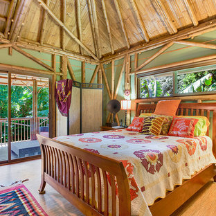 Imagen de habitación de invitados tropical con paredes verdes y suelo de bambú