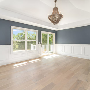 Großes Country Hauptschlafzimmer mit blauer Wandfarbe, hellem Holzboden, beigem Boden, gewölbter Decke und vertäfelten Wänden in Chicago