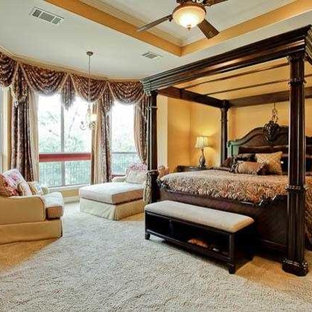 Immagine di una grande camera matrimoniale vittoriana con pareti gialle, moquette, camino lineare Ribbon, cornice del camino in metallo e pavimento beige