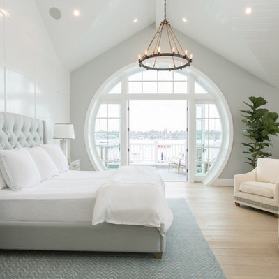 Example of a beach style light wood floor and beige floor bedroom design in Orange County with blue walls
