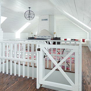 Modelo de dormitorio tipo loft, de estilo de casa de campo, grande, con paredes blancas, suelo de madera en tonos medios y suelo marrón