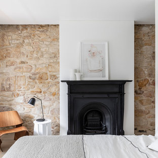 Photo of a contemporary bedroom in Sydney with white walls, light hardwood floors, a standard fireplace and beige floor.