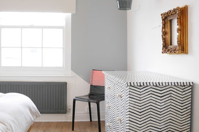 Small contemporary master bedroom in London with grey walls, laminate floors, no fireplace and brown floors.