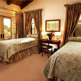 Inspiration for a large mediterranean guest bedroom in Seattle with beige walls, limestone floors, a stone fireplace surround and beige floor.
