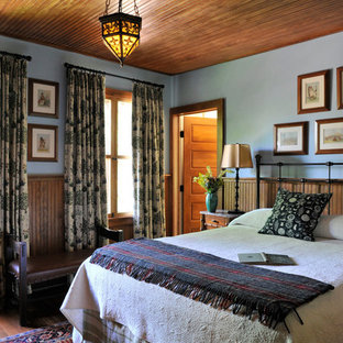 Ejemplo de dormitorio principal, rural, de tamaño medio, con paredes azules y suelo de madera oscura