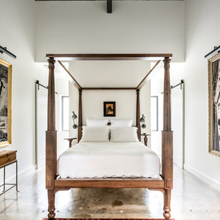 Immagine di una piccola camera da letto stile loft industriale con pareti bianche e pavimento in cemento