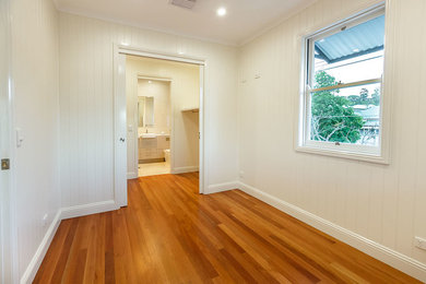 Ejemplo de dormitorio principal tradicional de tamaño medio sin chimenea con paredes blancas y suelo de madera en tonos medios