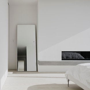 Foto di una camera matrimoniale contemporanea di medie dimensioni con pareti bianche, parquet chiaro, camino lineare Ribbon e cornice del camino in intonaco
