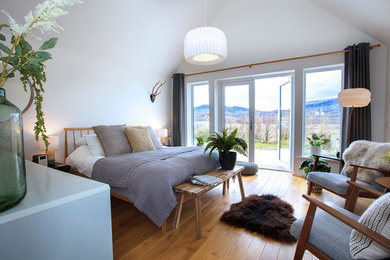 Diseño de dormitorio principal actual de tamaño medio con paredes blancas, suelo de madera en tonos medios y suelo marrón
