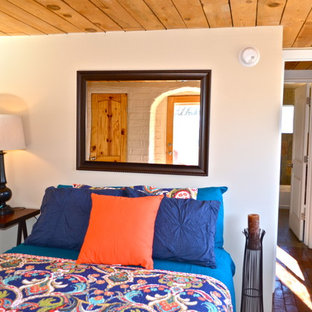 Imagen de dormitorio principal, de estilo americano, de tamaño medio, con paredes blancas y suelo de ladrillo