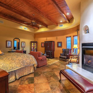 Diseño de dormitorio principal, de estilo americano, de tamaño medio, con paredes amarillas, suelo de pizarra, chimenea tradicional, marco de chimenea de yeso y suelo multicolor
