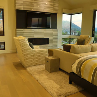 Modelo de dormitorio principal, clásico renovado, grande, con paredes beige, suelo de madera clara, chimenea lineal y marco de chimenea de baldosas y/o azulejos
