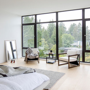 Großes Modernes Hauptschlafzimmer mit weißer Wandfarbe, hellem Holzboden, Hängekamin, Kaminumrandung aus Metall und beigem Boden in Vancouver