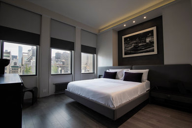 Large minimalist guest laminate floor and gray floor bedroom photo in New York with gray walls