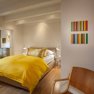 Imagen de dormitorio principal, contemporáneo, de tamaño medio, sin chimenea, con paredes blancas, suelo de madera clara y suelo marrón