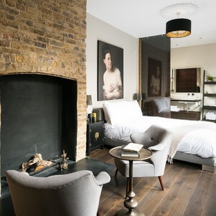 Diseño de dormitorio principal, mediterráneo, con suelo de madera oscura, chimenea tradicional, marco de chimenea de ladrillo, paredes beige y suelo marrón