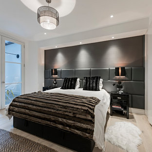 This is an example of a medium sized contemporary bedroom in London with white walls, light hardwood flooring and beige floors.