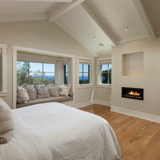Großes Klassisches Hauptschlafzimmer mit Gaskamin, beiger Wandfarbe, braunem Holzboden und verputzter Kaminumrandung in Santa Barbara