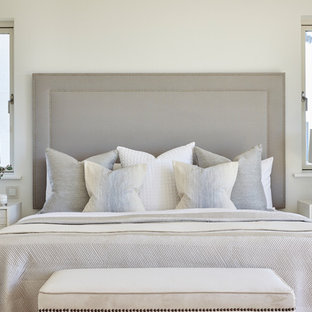 This is an example of a beach style master bedroom in London with white walls, light hardwood flooring and no fireplace.