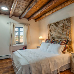 Idée de décoration pour une petit chambre parentale sud-ouest américain avec un mur beige, un sol en bois brun, aucune cheminée et un sol marron.