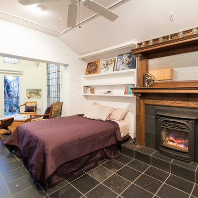 Example of a large eclectic master bedroom design in San Francisco with white walls and a standard fireplace