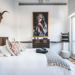 Immagine di una camera matrimoniale boho chic con pareti bianche, pavimento in legno massello medio e pavimento marrone