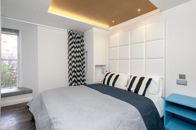 Small contemporary master bedroom in Edinburgh with white walls, laminate floors and brown floors.