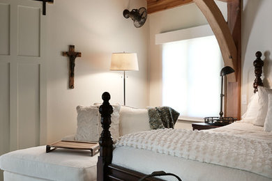 Modelo de dormitorio principal rural grande con paredes beige, suelo de madera en tonos medios y suelo marrón