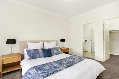 Foto de dormitorio principal moderno de tamaño medio sin chimenea con paredes blancas, moqueta y suelo marrón