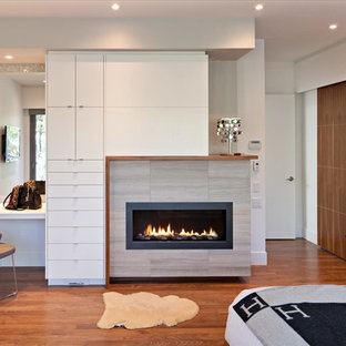 Cette photo montre une chambre parentale tendance de taille moyenne avec un mur blanc, un sol en bois foncé, une cheminée ribbon, un manteau de cheminée en carrelage et un sol beige.
