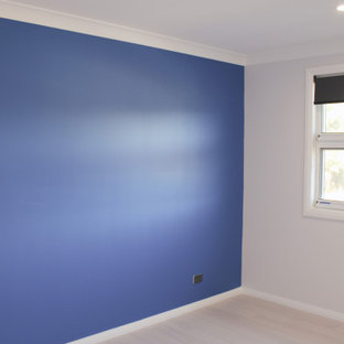 Modelo de habitación de invitados minimalista, de tamaño medio, con paredes azules y suelo de madera clara
