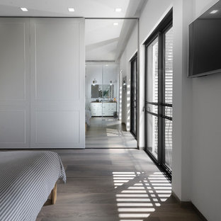 Imagen de habitación de invitados contemporánea, grande, sin chimenea, con paredes blancas y suelo de contrachapado