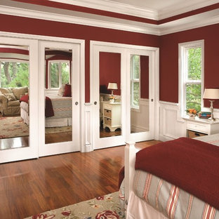 Diseño de dormitorio tradicional renovado con paredes rojas y suelo de madera en tonos medios