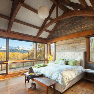 Imagen de dormitorio principal, rústico, grande, sin chimenea, con paredes marrones, suelo de madera clara y suelo marrón