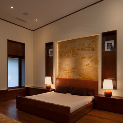 Trendy master medium tone wood floor bedroom photo in New York with beige walls