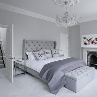This is an example of a contemporary master bedroom in London with grey walls, carpet, a standard fireplace and grey floors.
