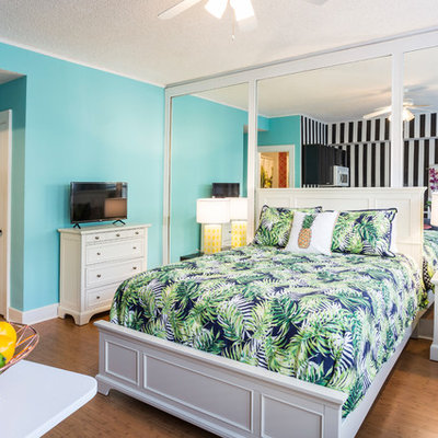 Island style medium tone wood floor and brown floor bedroom photo in Miami with blue walls