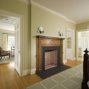 Modelo de habitación de invitados tradicional, grande, con paredes beige, suelo de madera en tonos medios, chimenea tradicional y marco de chimenea de madera