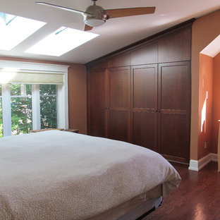 Imagen de dormitorio tipo loft, de estilo americano, pequeño, sin chimenea, con parades naranjas, suelo de madera en tonos medios y suelo marrón