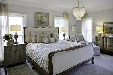 Modelo de dormitorio principal clásico de tamaño medio con paredes grises y suelo de madera en tonos medios