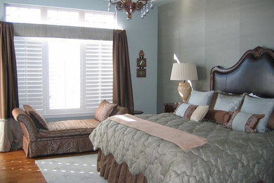 Cette image montre une chambre parentale traditionnelle de taille moyenne avec un mur bleu, un sol en bois brun et un sol marron.