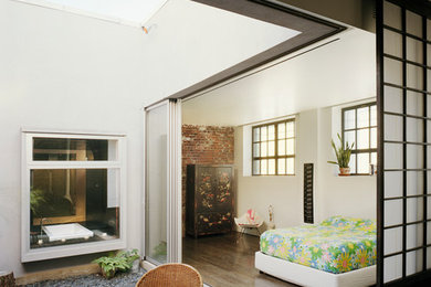 ニューヨークにある広いインダストリアルスタイルのおしゃれな主寝室 (白い壁、濃色無垢フローリング、茶色い床、暖炉なし) のインテリア